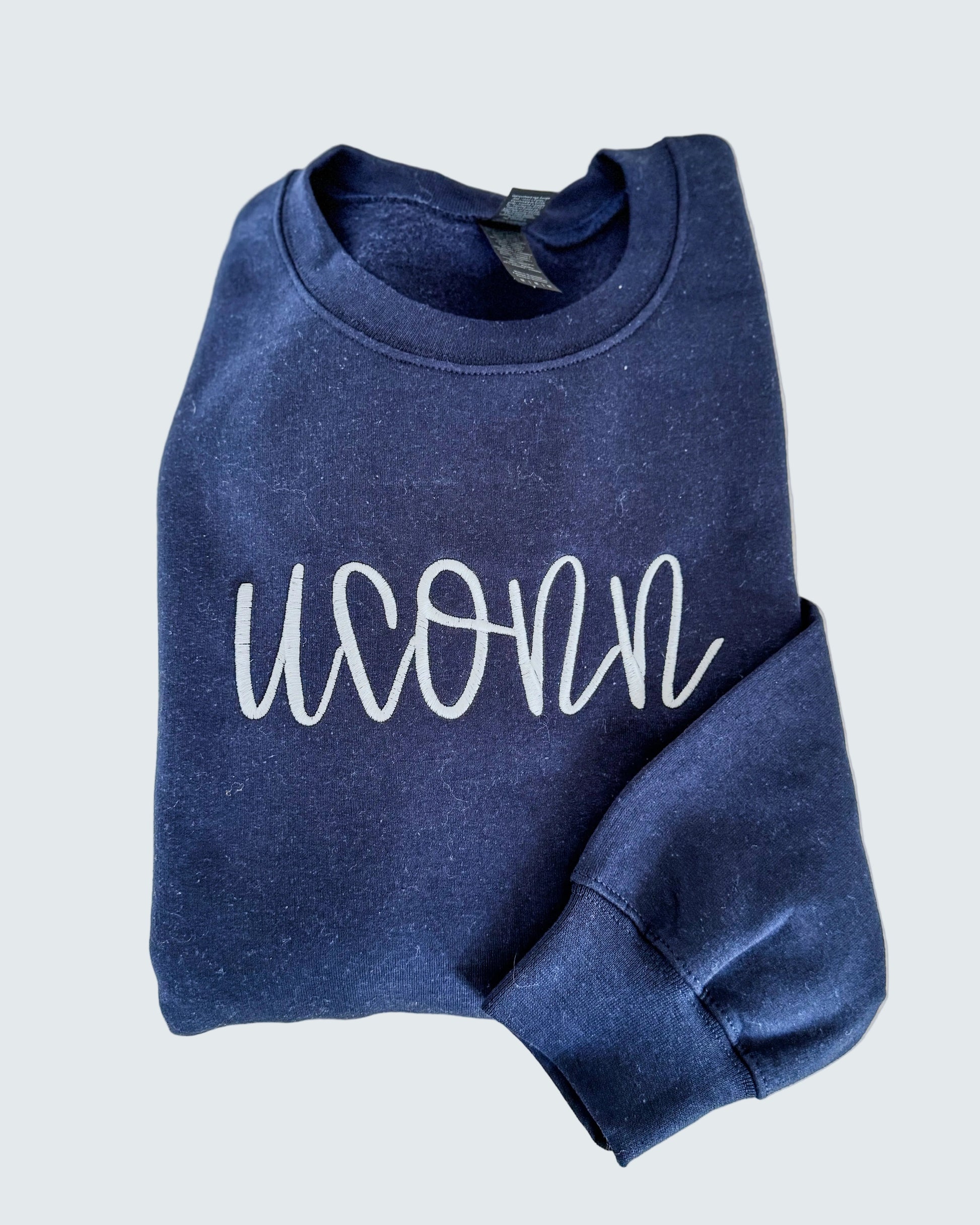 Blue sweatshirt with 'UCONN' text on a light wooden surface