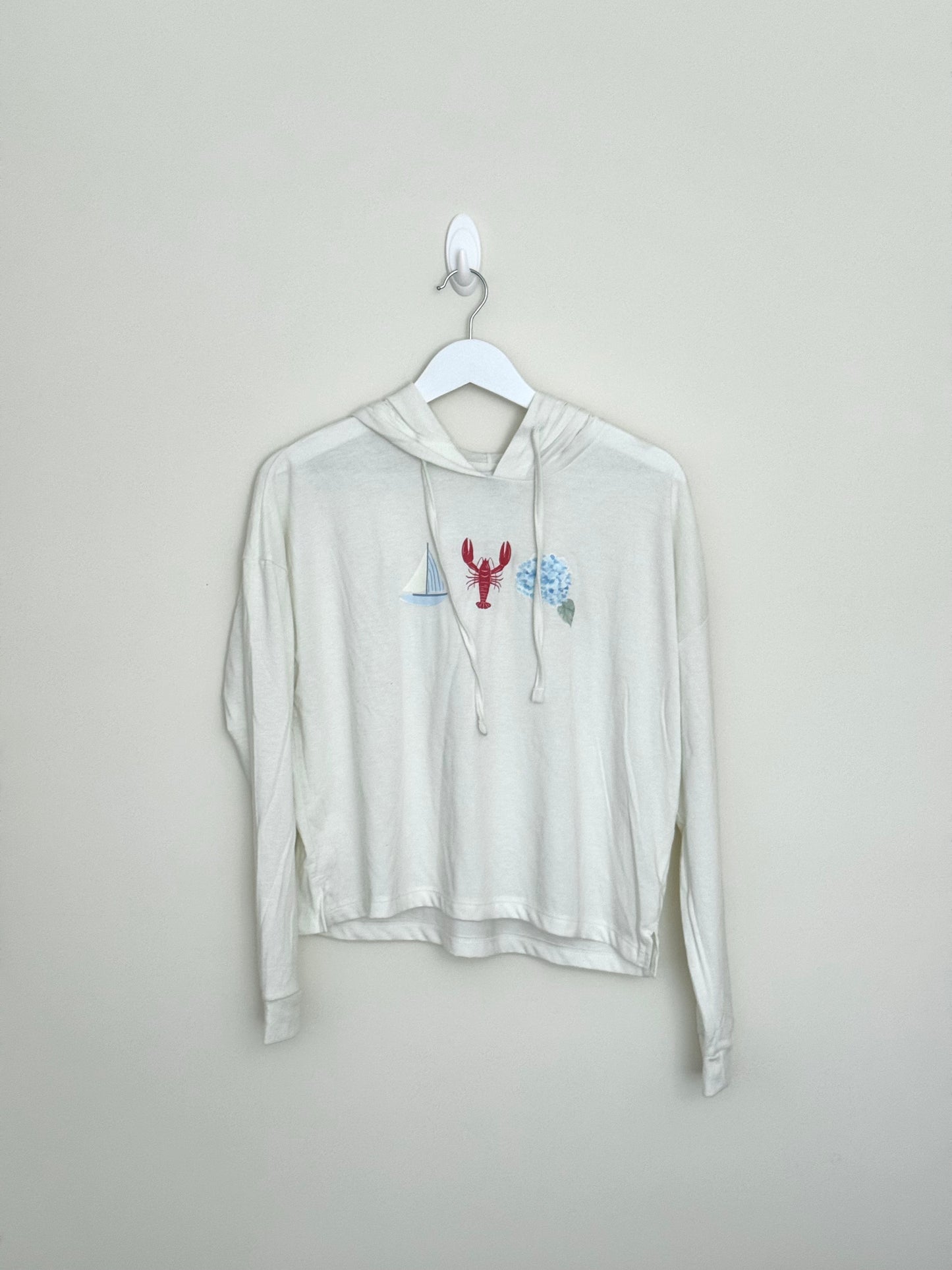 White hoodie with a graphic design on a hanger against a plain background