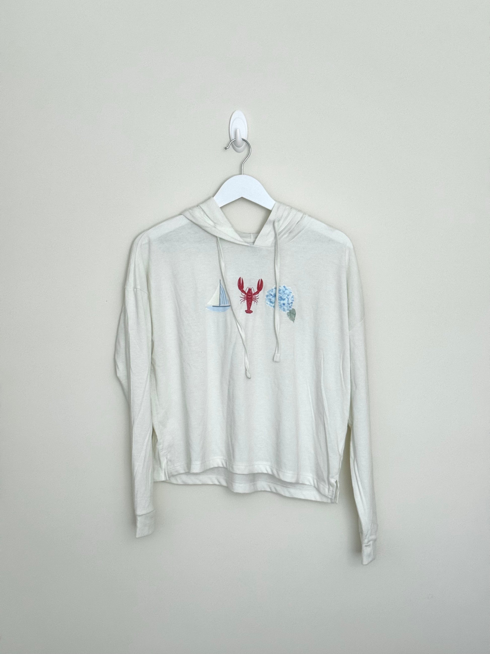 White hoodie with a graphic design on a hanger against a plain background