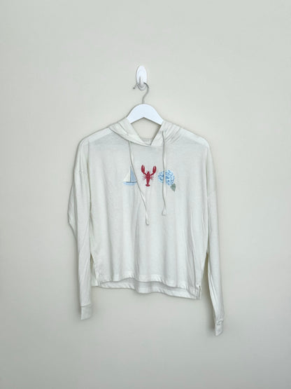 White hoodie with a graphic design on a hanger against a plain background
