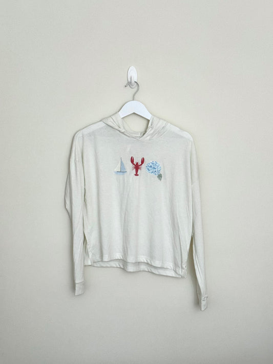 Beige long-sleeve shirt with graphic design on a hanger against a beige background